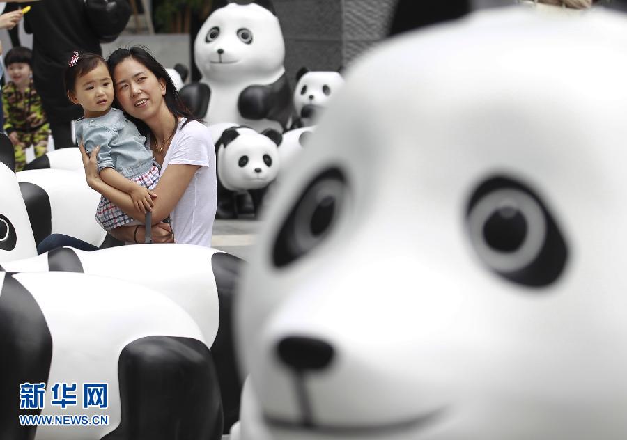 6月2日，一位家長(zhǎng)帶著孩子在上海街頭和大熊貓模型合影。