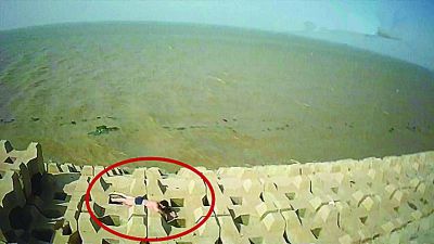 孫正龍游上岸，趴在海邊精疲力盡。