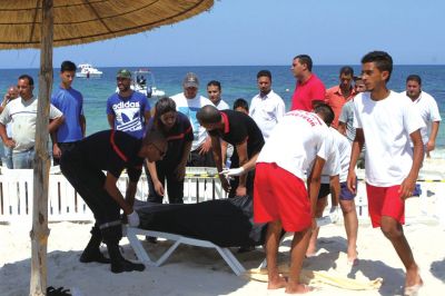 6月26日，在突尼斯蘇塞，救生員和醫(yī)務(wù)人員在發(fā)生襲擊事件的海灘運(yùn)送一名死者的遺體。新華社發(fā)