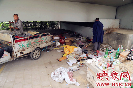 負(fù)責(zé)高架橋下綠化的人員在清理流浪漢留下的垃圾和雜物。