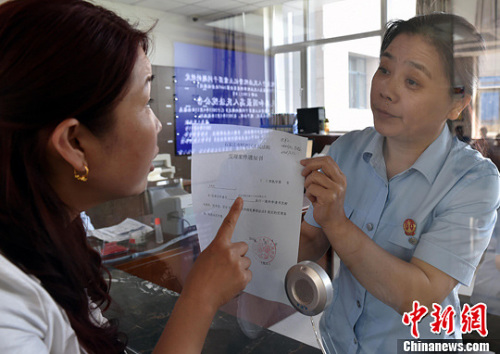 資料圖：2015年5月4日，河北石家莊市橋西區(qū)人民法院立案庭庭長齊燕正在為立案人辦理相關(guān)手續(xù)，完成整個過程只用了5分鐘。當(dāng)日是立案登記制改革首個工作日，該院共立案36件，立案率達(dá)到90%。中新社發(fā) 翟羽佳 攝