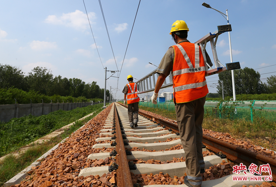 滾燙的鐵軌上，兩個扛著梯子的檢修員走向第四個檢修點