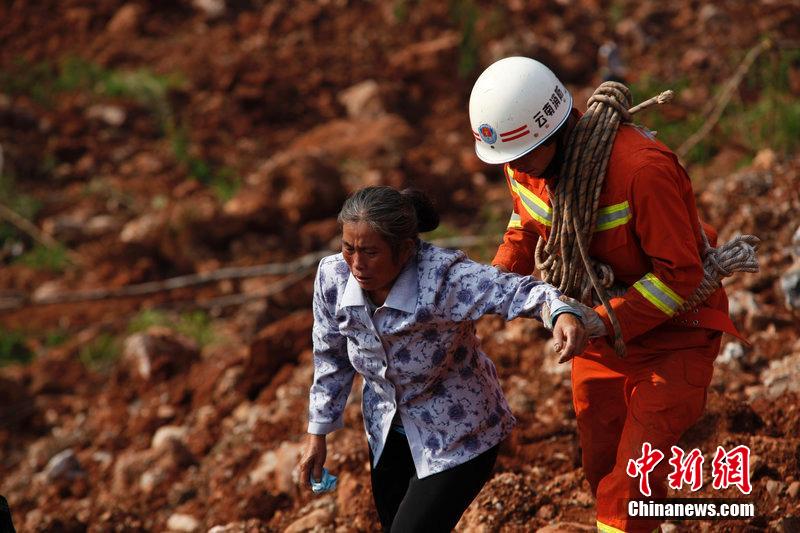 一位消防戰(zhàn)士將一位失去親人的老人扶離滑坡點。