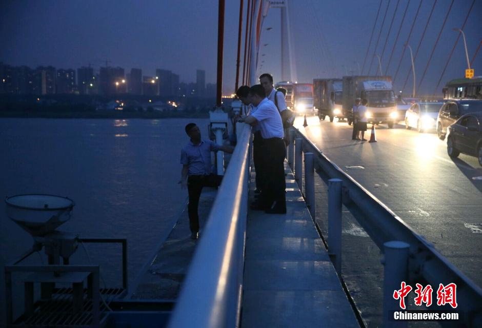 圖為武漢警方談判專家正在與翻爬至大橋外側(cè)護欄的劫持者談判。