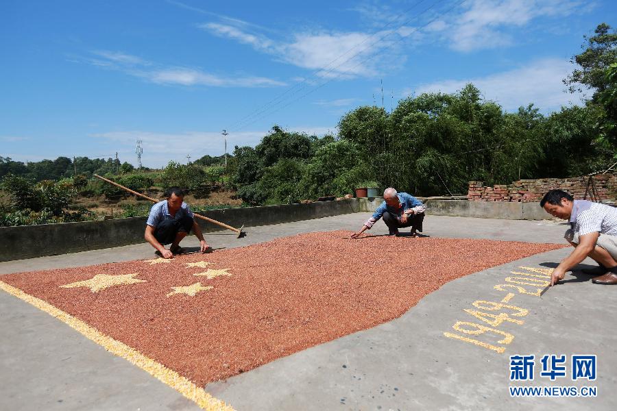 村民馬玉明（左一）用豐收的高粱和玉米在院壩里擺國旗為祖國慶生。