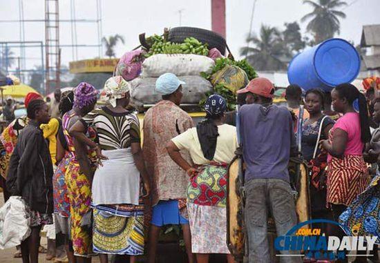 當(dāng)?shù)貢r(shí)間2014年8月14日，利比里亞蒙羅維亞，市場(chǎng)里的商人們圍著一輛汽車。