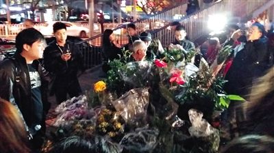 昨晚7時許，三里屯太古里西邊附近一過街天橋旁邊，聞訊而至的網友圍住了賣花老人，爭相買花。 網友“行者橙子”供圖