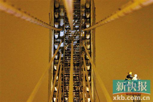 截至今日零時，男子仍未有下橋舉動。圖為公安和消防人員乘消防云梯在高空上和男子交談。