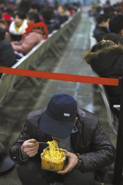 北京西站臨時(shí)候車(chē)廳，鄧軍吃著妻子泡好的方便面